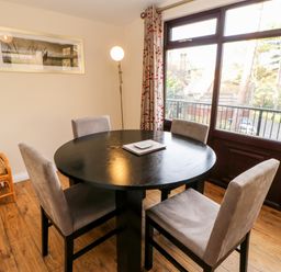 A dining room with a round black table and four chairs near a window at Violet Lodge in Saltburn-by-the-Sea
