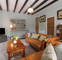 A living room with brown leather sofas a wooden coffee table a tv on a chest and a grey cabinet at Beck Cottage in Pickering
