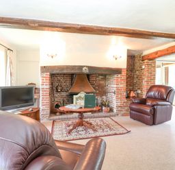 A living room with leather chairs a wooden coffee table and a brick fireplace at Lyons Green in Little Fransham near Swaffham