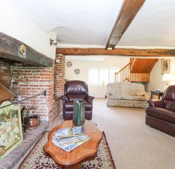 A living room with leather armchairs a floral sofa wooden coffee table and exposed wooden beams at Lyons Green in Little Fransham near Swaffham