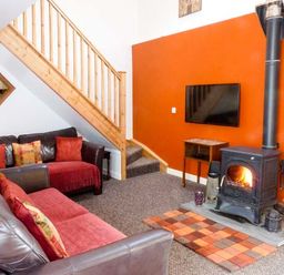 A living room with two sofas a wood stove and a wall mounted TV at Woodstone Barn Whitchurch near Tavistock