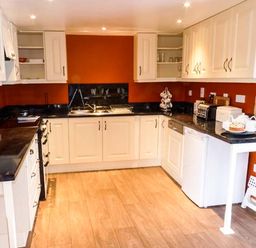 A kitchen with white cabinets black countertops and orange walls at Woodstone Barn Whitchurch near Tavistock