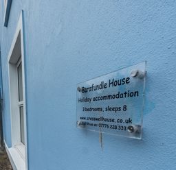 A blue exterior wall with a sign for Barafundle House holiday accommodation in Tenby
