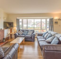 A living room with brown leather sofas a wooden coffee table a brick fireplace and a television at Dune View in Beadnell