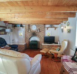 A living room with a fireplace and television at Fuschia Cottage, Waterville, County Kerry