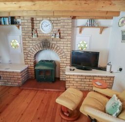 A living room with a fireplace and television at Fuschia Cottage in Waterville, County Kerry