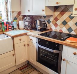 A kitchen corner with a sink oven stovetop and countertop appliances at Lothlorien Cottage in Cwmgors near Ammanford