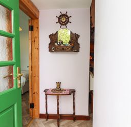 A hallway with a wooden table and a mirror with nautical decorations at Brendan's Cottage in Valentia Island County Kerry