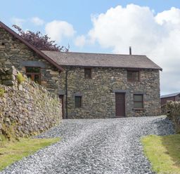 A building with stone walls and a gravel path at Copper Beech Cottage in Torver