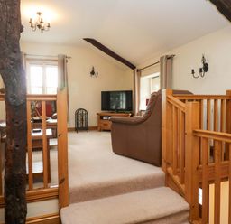 A living room with a television and sofa at Copper Beech Cottage in Torver