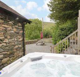 An outdoor area with a hot tub and a picnic table at Yew Tree Cottage Torver