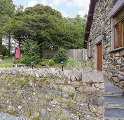 An outdoor area with a stone wall and garden furniture at Yew Tree Cottage Torver