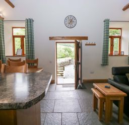 A living room with a door leading outside at Yew Tree Cottage in Torver
