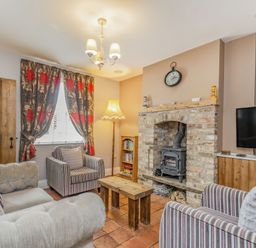 A living room with armchairs a sofa a wooden coffee table a brick fireplace and a television at Fisher Cottage in Hornsea