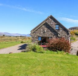 A house with a driveway and grass surrounding it at Stone Cottage in Waterville, County Kerry