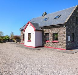 A house with stone walls and a gravel driveway at Stone Cottage in Waterville, County Kerry