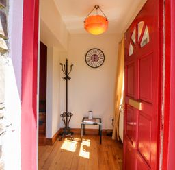 A hallway with a red door and a clock at Stone Cottage in Waterville, County Kerry