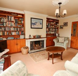 A living room with bookshelves a fireplace and seating at The Lodge in Churchtown near Beaufort County Kerry