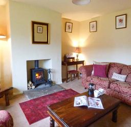 A living room with a fireplace wooden coffee table and patterned sofa at The White Cottage in Bridlington