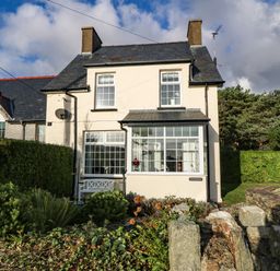 A two-story house with large windows and a garden with shrubs and rocks at Ty'r Ysgol in Morfa Bychan