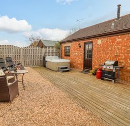 An outdoor patio area with chairs a table a hot tub and a barbecue grill at Dairy Barn in Pershore