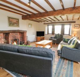 A living room with a brick fireplace gray sofas a wooden coffee table and a television at Hadrians View in Banks near Brampton
