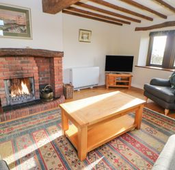 A living room with a fireplace and wooden beams at Hadrians View Banks near Brampton