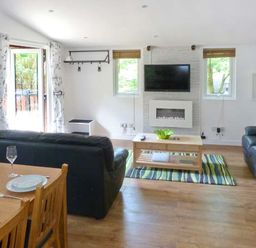 A living room with black leather sofas a wooden coffee table and a wall mounted television at Top Lodge 4 Skiptory Howe White Cross Bay near Troutbeck Bridge