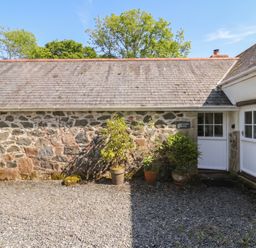 An outdoor area with stone wall and plants at Swallows, St Keverne, Lizard Peninsula
