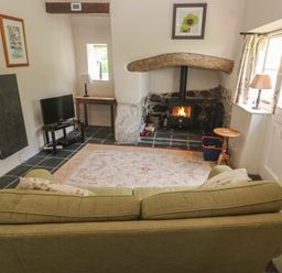 A living room with a wood stove and television at Swallows St Keverne, Lizard Peninsula