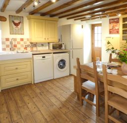 A kitchen with yellow cabinets wooden dining table and chairs and appliances at Fell View Cottage in Bootle near Millom
