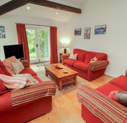 A living room with red sofas and a coffee table at Winster Fields in Cartmel Fell near Windermere
