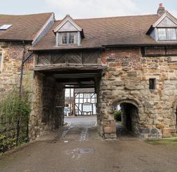 An old stone archway building with a passage and windows at Porters Lodge in Polesworth