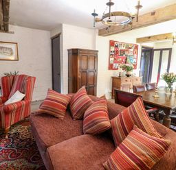 A living room and dining area with wooden table chairs sofa armchair and cushions at Gatehouse Croft in Polesworth