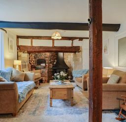 A living room with sofas, a coffee table, and a fireplace at Church Farmhouse in Winsham