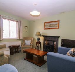 A living room with a sofa, armchair, coffee table, and fireplace at The Lock House in Gloucester