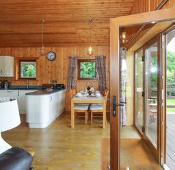 Kitchen and dining area with wooden walls and ceiling at Barn Shelley Lodge in Copplestone near Crediton