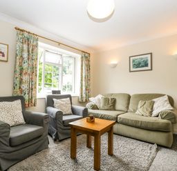 A living room with two armchairs a sofa and a wooden table at Wye Valley Cottage in Symonds Yat