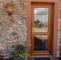 An entryway with a wooden door and flower pot at Piggery Cottage Wigton