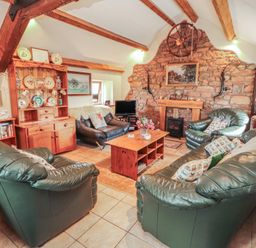 A living room with green sofas and a fireplace at Piggery Cottage in Wigton
