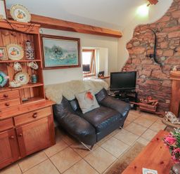 A living room with a sofa and a television at Piggery Cottage in Wigton