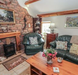 A living room with a sofa and fireplace at Piggery Cottage in Wigton