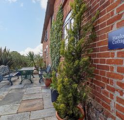 An outdoor patio with stone flooring metal benches and table and plants at Hayloft Cottage Little Glemham near Wickham Market