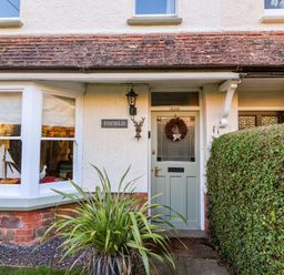 Front entrance of a house with a green door and bay window with a model sailboat at Enfield in Porlock