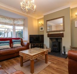 A living room with leather sofas a wood stove and a wooden coffee table at Enfield in Porlock