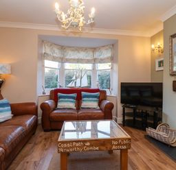 A living room with brown leather sofas a wooden coffee table and a television at Enfield in Porlock