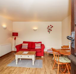 A living room with a red sofa table and chairs at Poppy Cottage in Little Glemham near Wickham Market