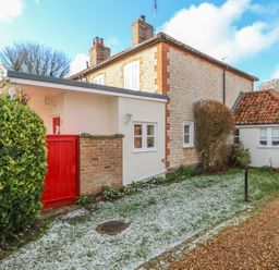 A stone and brick house with a red gate and gravel path at 28 Oxborough in Oxborough