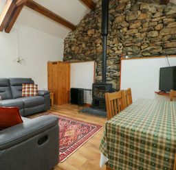 A living room with a sofa, television, and dining table at Bythyn Ddol Hafod in Capel Curig