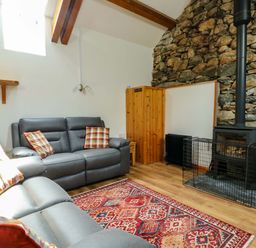 A living room with a sofa and a fireplace at Bythyn Ddol Hafod in Capel Curig